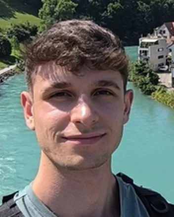 Retrato de Íñigo Guzmán, sonriendo, junto a un río de agua turquesa.
